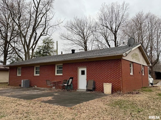 back of property featuring brick siding, a yard, and central AC