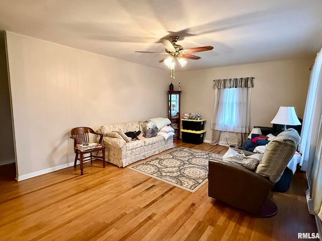 living room with a ceiling fan, baseboards, and wood finished floors