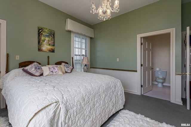 carpeted bedroom featuring ensuite bathroom, baseboards, and an inviting chandelier