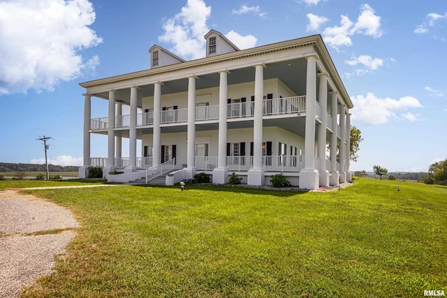 back of house with covered porch, a lawn, and a balcony