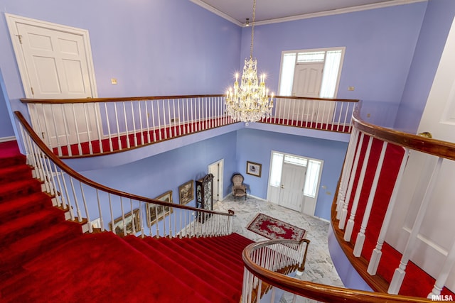 entryway featuring a chandelier, ornamental molding, stairway, and a towering ceiling