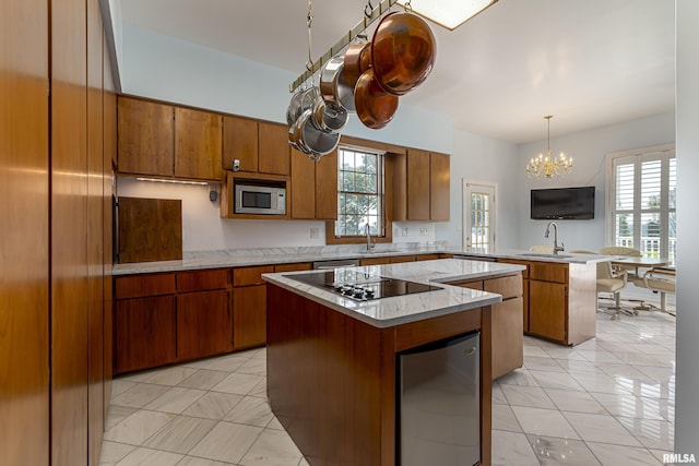 kitchen with a peninsula, a kitchen island, a sink, brown cabinets, and built in microwave