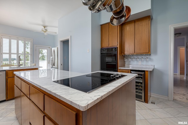 kitchen with brown cabinetry, a kitchen island, a sink, black appliances, and backsplash