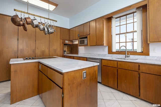 kitchen featuring brown cabinets, light countertops, appliances with stainless steel finishes, a sink, and a kitchen island