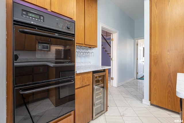 kitchen with wine cooler, marble finish floor, brown cabinets, light countertops, and dobule oven black