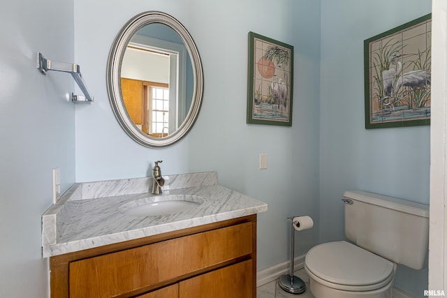 half bath with toilet, baseboards, and vanity