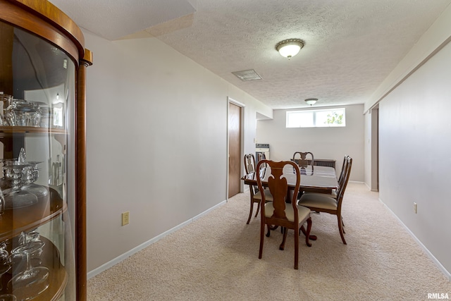 dining area with light carpet, visible vents, baseboards, and a textured ceiling