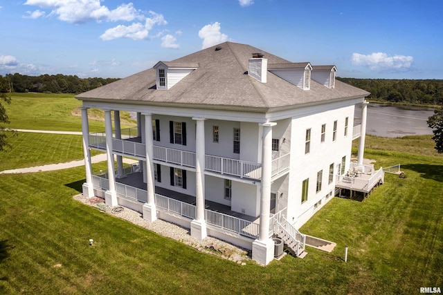 back of property featuring a chimney, a porch, a shingled roof, a water view, and a lawn