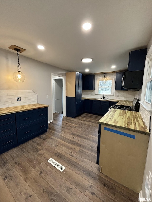 kitchen featuring visible vents, black microwave, range with gas stovetop, and dark wood-type flooring