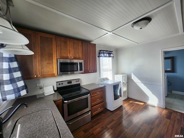 kitchen with washer / dryer, dark countertops, dark wood-style floors, appliances with stainless steel finishes, and a sink