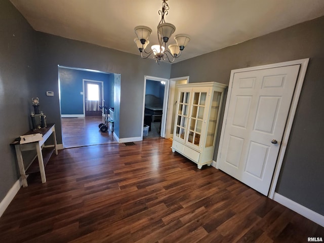 interior space with a notable chandelier, wood finished floors, and baseboards