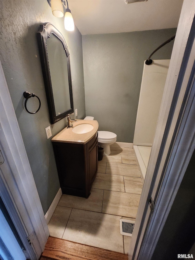 full bathroom featuring baseboards, visible vents, a shower, toilet, and vanity