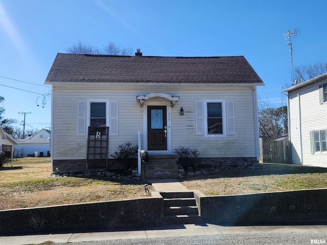 bungalow featuring entry steps, a shingled roof, a chimney, fence, and a front yard