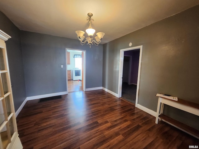 empty room with baseboards, dark wood-style flooring, and an inviting chandelier