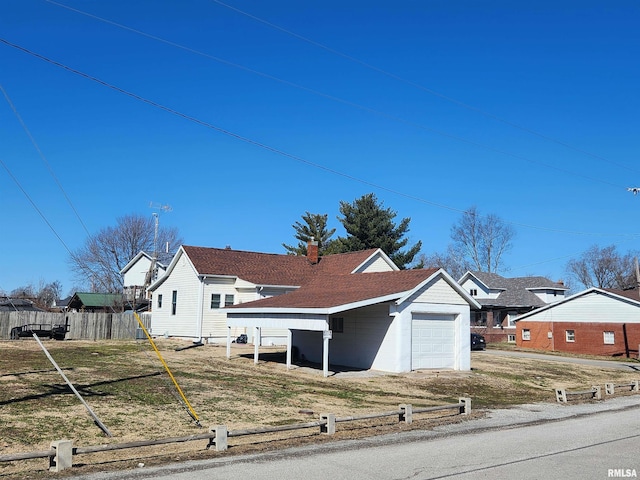 view of front facade featuring a chimney, a shingled roof, an attached garage, fence, and driveway