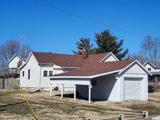 view of side of home featuring a shingled roof, fence, a chimney, and an attached garage