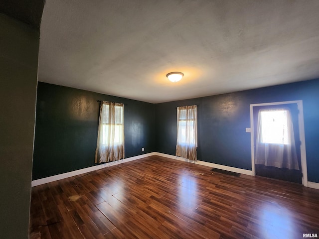 unfurnished room featuring plenty of natural light, baseboards, and wood finished floors