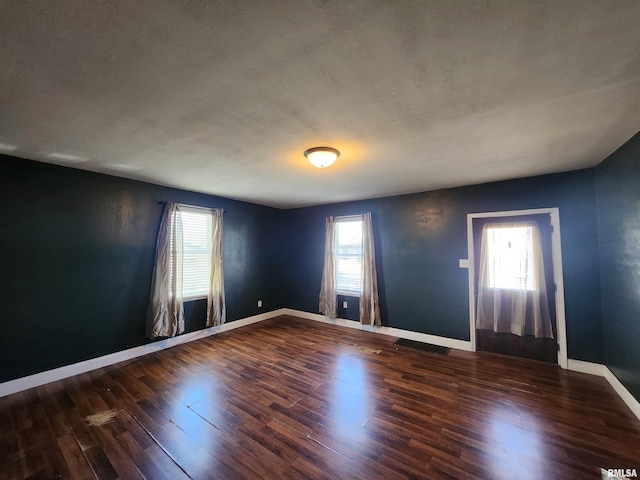 spare room featuring plenty of natural light, wood finished floors, and baseboards