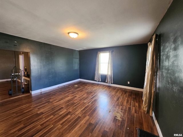 unfurnished room featuring visible vents, baseboards, and wood finished floors