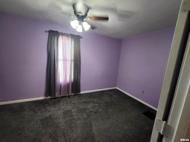 empty room featuring ceiling fan, visible vents, baseboards, and dark carpet