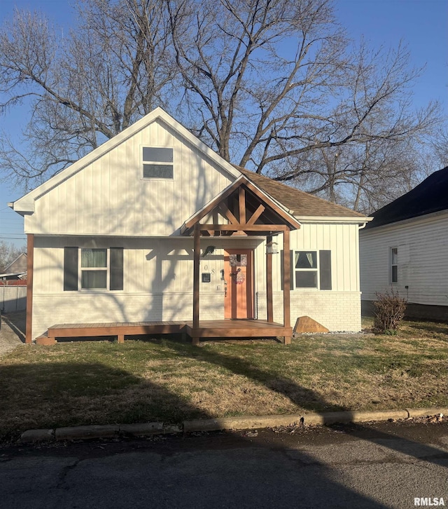 view of front of house featuring roof with shingles, a front lawn, and brick siding