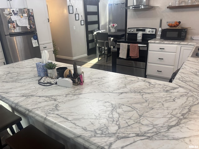 kitchen with light stone counters, open shelves, stainless steel appliances, white cabinetry, and wall chimney exhaust hood