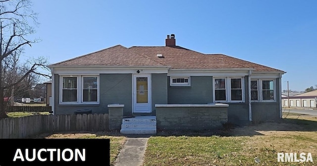 bungalow-style home featuring a chimney, fence, a front lawn, and roof with shingles