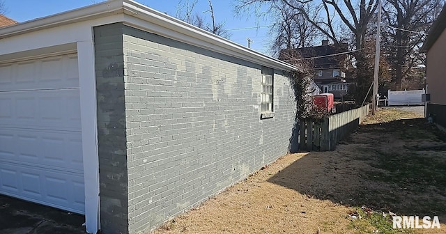 view of property exterior with a garage, fence, and brick siding