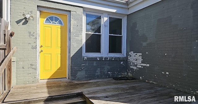 entrance to property featuring brick siding and a deck