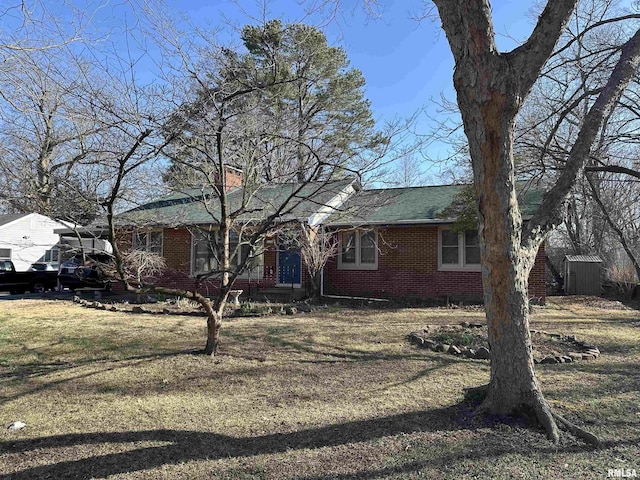 ranch-style house featuring brick siding, a chimney, and a front yard