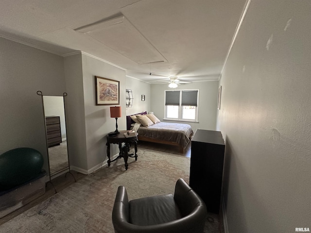 carpeted bedroom with ceiling fan, baseboards, attic access, and crown molding