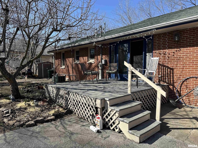 exterior space featuring a shingled roof, a deck, and brick siding