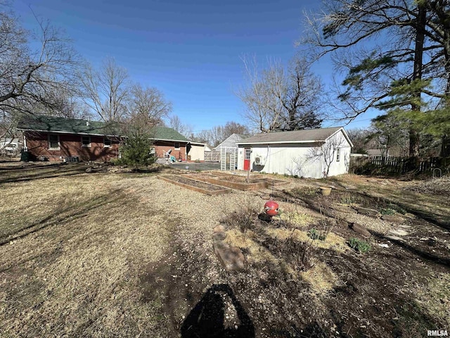 back of house featuring an outdoor structure, a vegetable garden, and fence