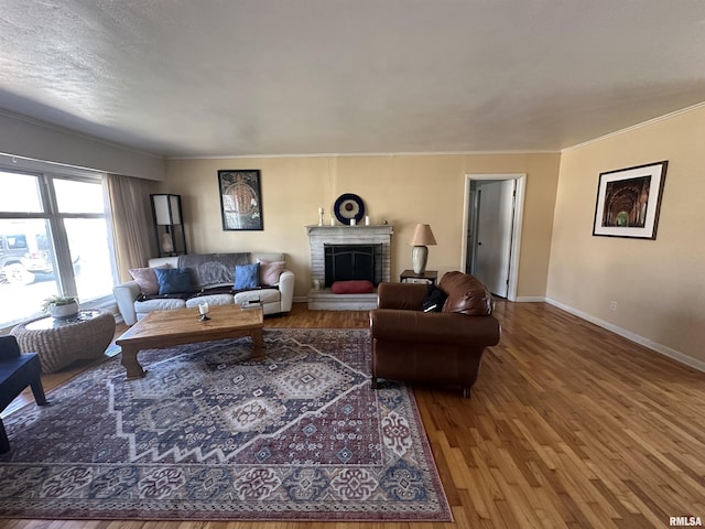 living room with crown molding, a fireplace, baseboards, and wood finished floors