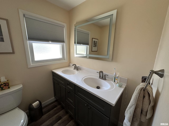 bathroom with toilet, double vanity, a sink, and wood finished floors