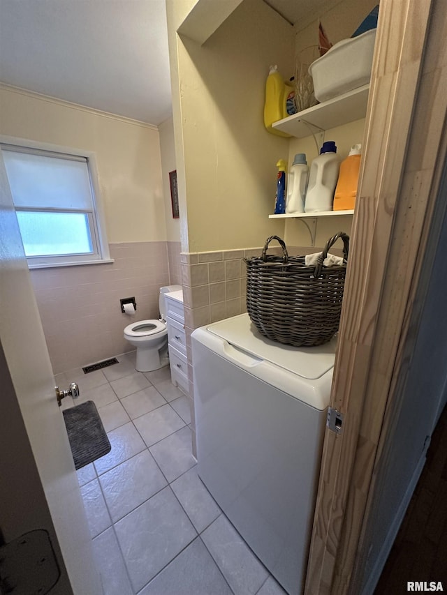 bathroom featuring tile walls, visible vents, wainscoting, washer / dryer, and tile patterned floors