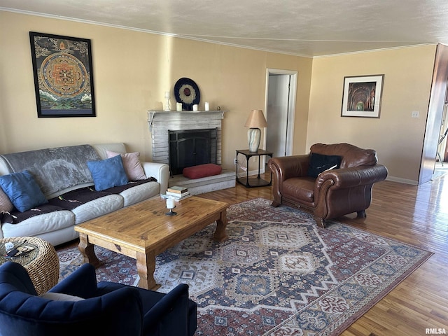 living room with ornamental molding, a fireplace, wood finished floors, and baseboards