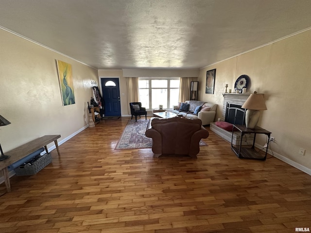 living area with crown molding, a fireplace, baseboards, and wood finished floors