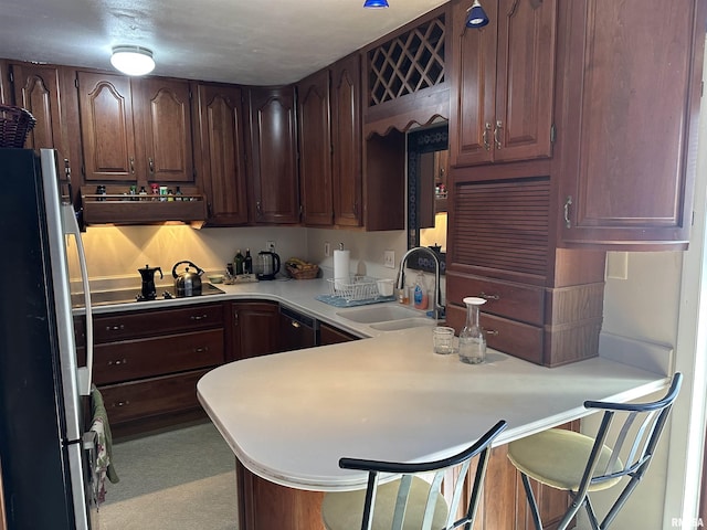 kitchen with freestanding refrigerator, a peninsula, black electric stovetop, ventilation hood, and a sink