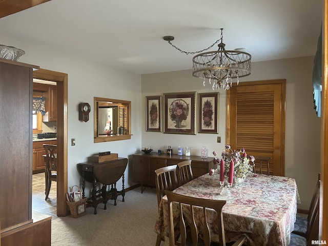 carpeted dining space featuring a chandelier and baseboards