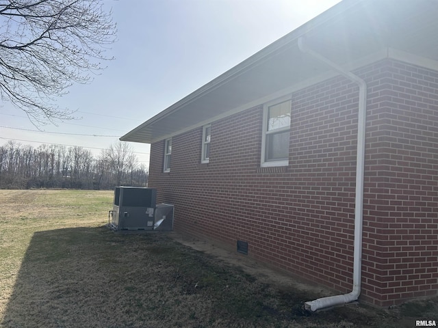 view of property exterior with crawl space, a lawn, cooling unit, and brick siding