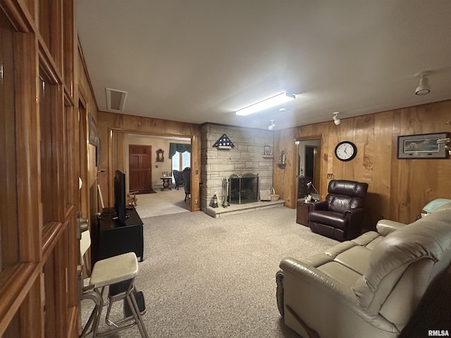 living room with a stone fireplace, wood walls, carpet flooring, and visible vents