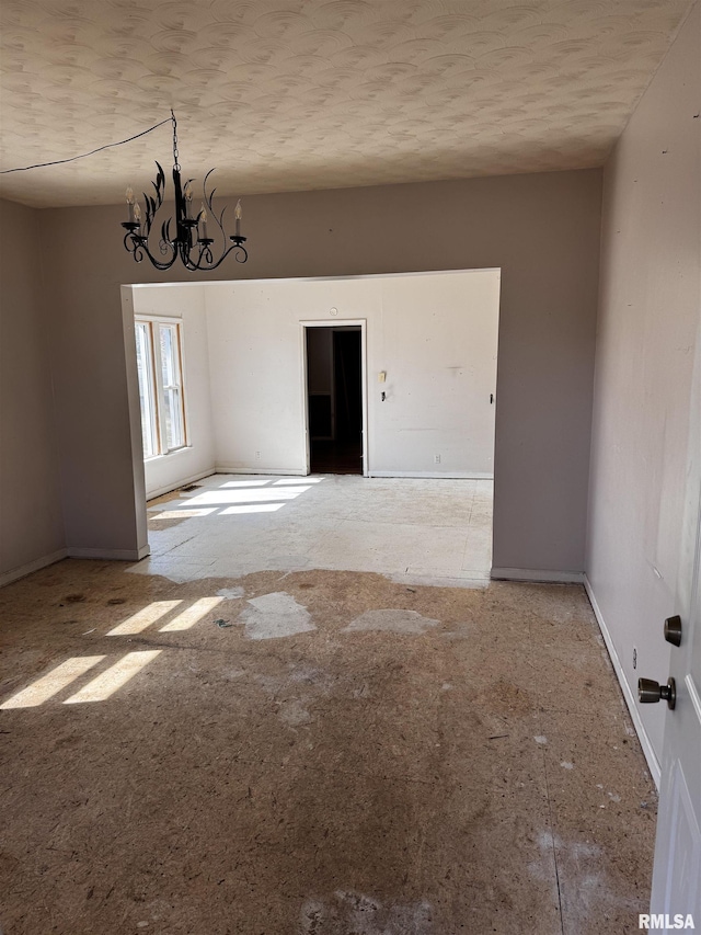 empty room featuring an inviting chandelier and baseboards