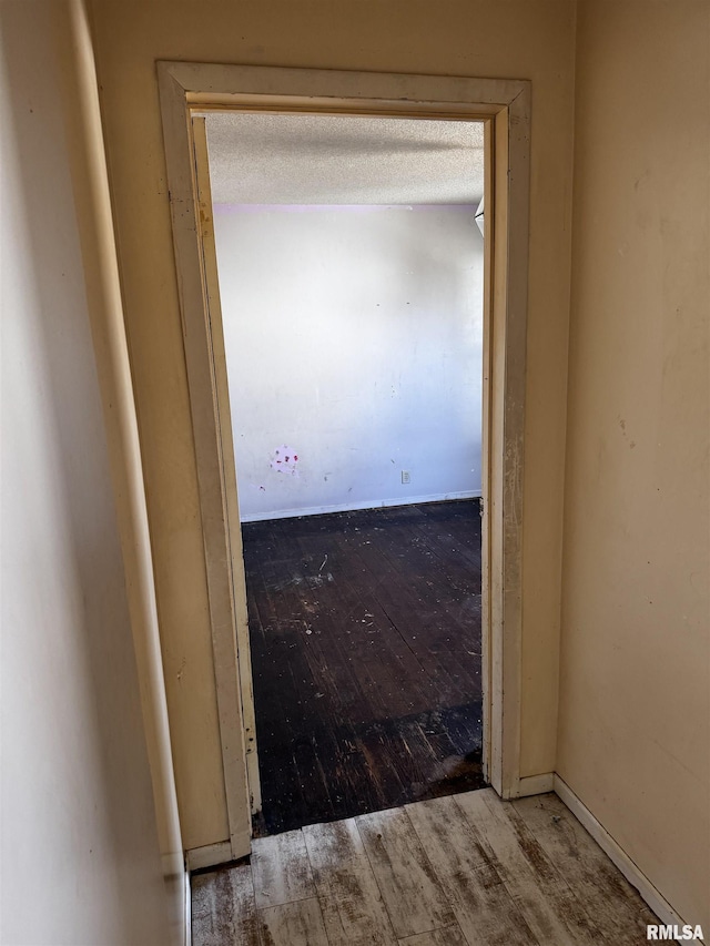 hallway featuring wood-type flooring and a textured ceiling