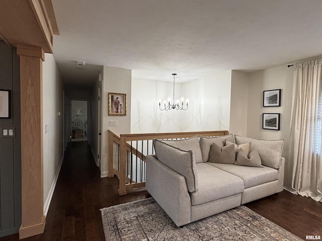 living room featuring a notable chandelier, baseboards, and wood finished floors