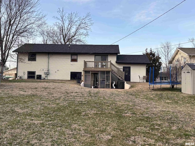 back of house featuring a lawn, stairway, an outbuilding, a trampoline, and a storage unit