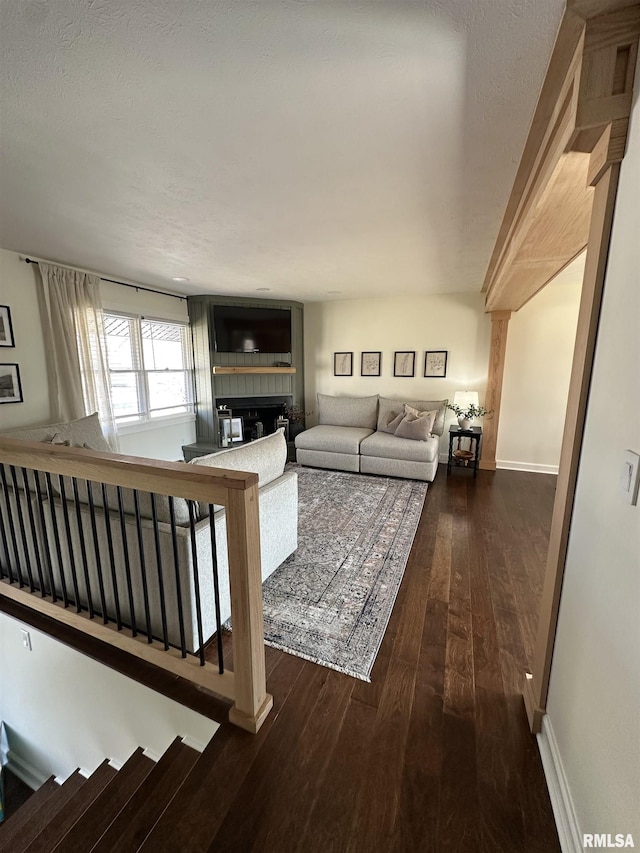 living room featuring a fireplace, stairway, baseboards, and wood finished floors