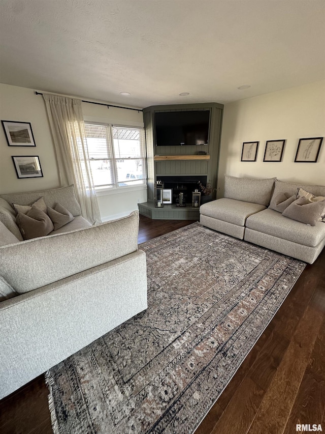 living area with dark wood finished floors and a tiled fireplace