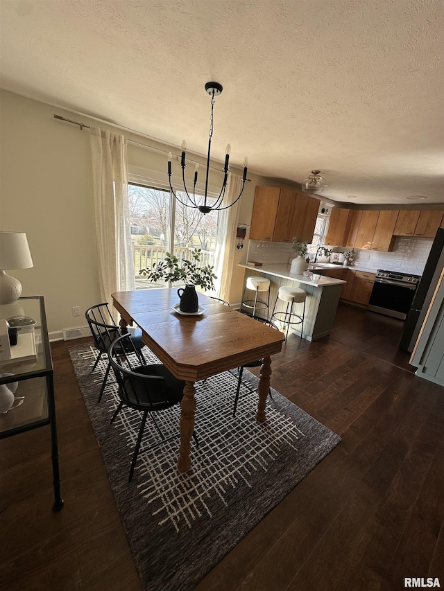 dining room with a textured ceiling, dark wood-type flooring, and plenty of natural light