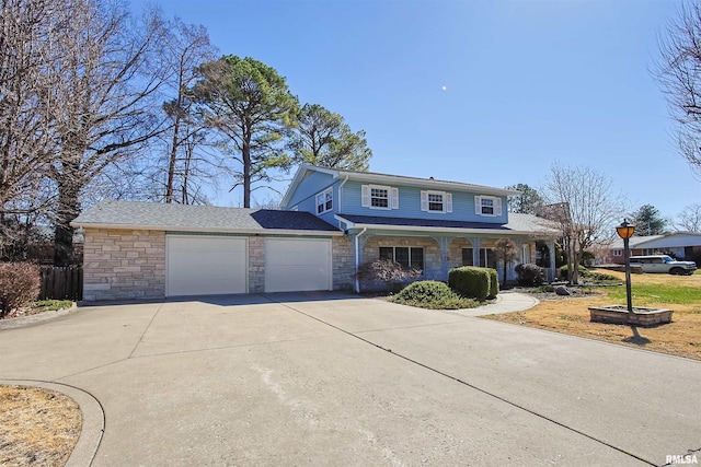 traditional-style home featuring a garage, stone siding, driveway, and covered porch